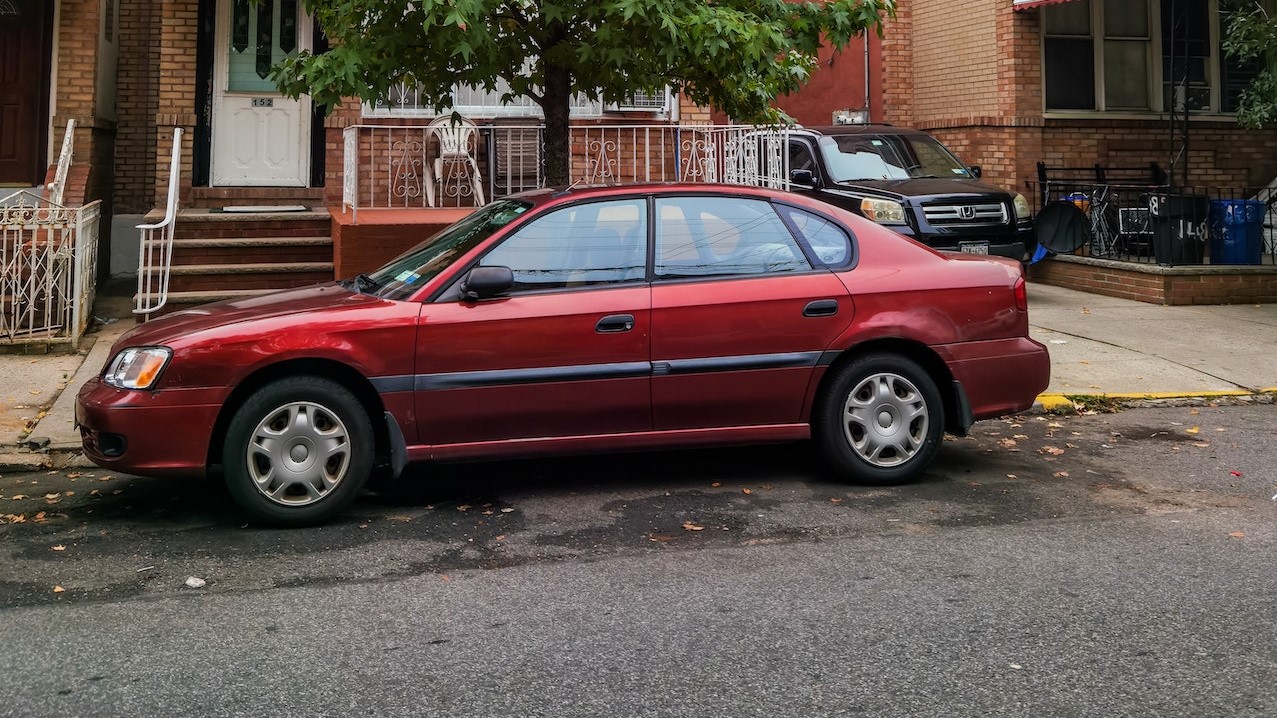 Red Sedan Parked Beside Green Tree | Goodwill Car Donations