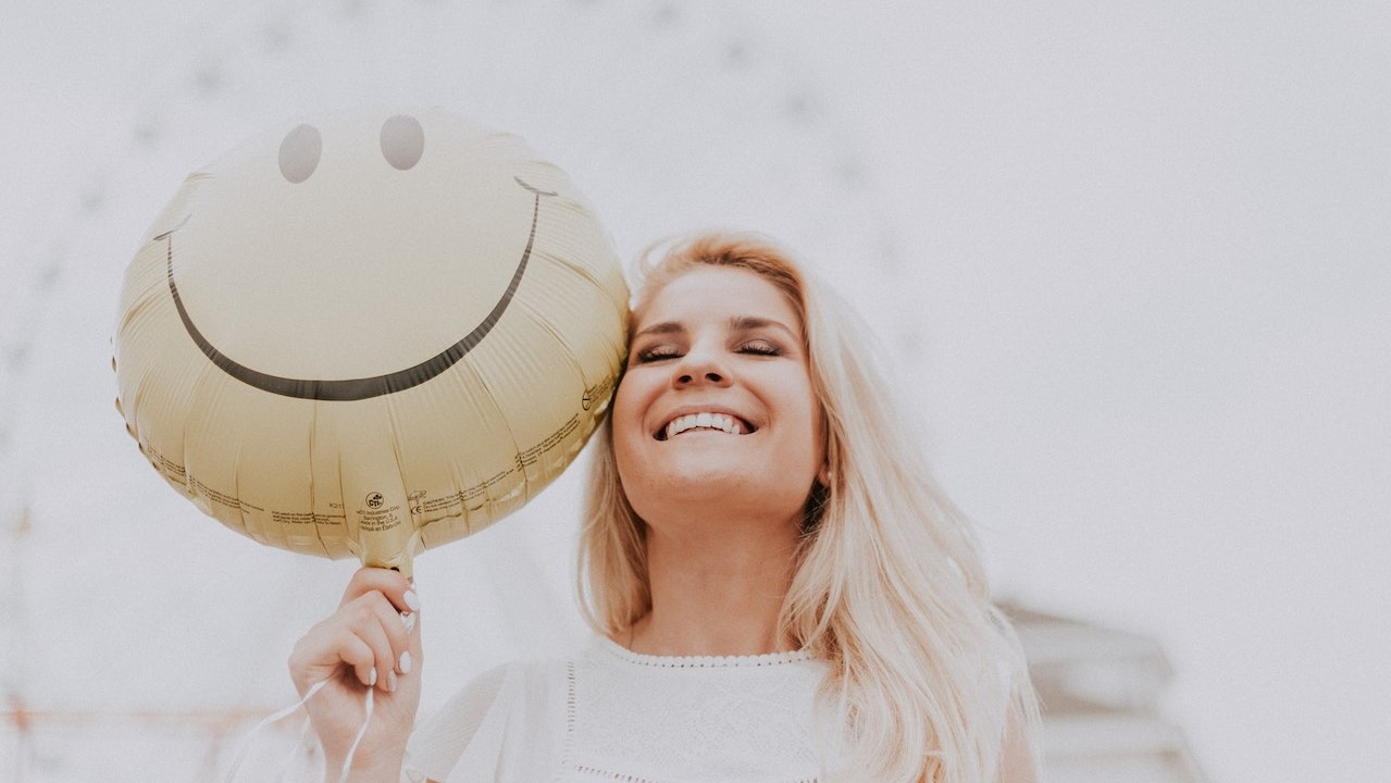 Woman Holding a Smiley Balloon | Goodwill Car Donations