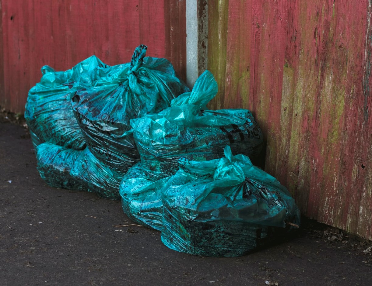 Green Plastic Bags Near a Wall | Goodwill Car Donations