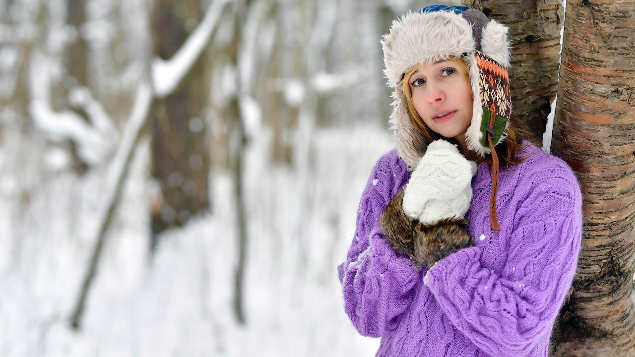 A Woman in a Snow Cap Leaning on a Tree Trunk | Goodwill Car Donations