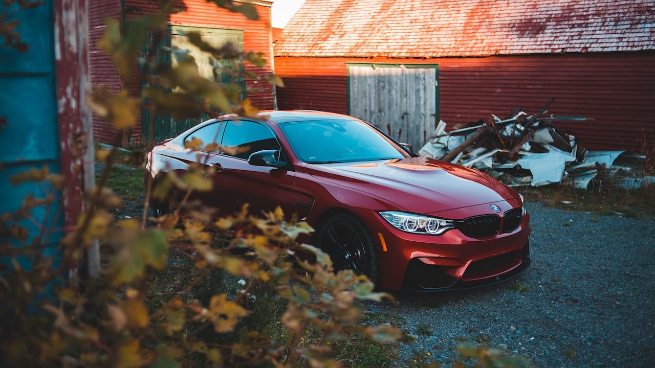Trendy red coupe car parked near abandoned barns in countryside | Goodwill Car Donations