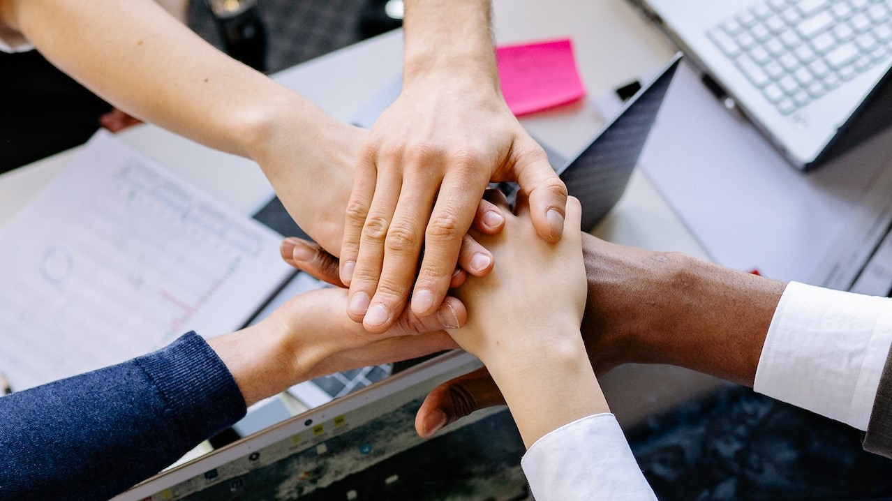 A Group of People Stacking Hands | Goodwill Car Donations