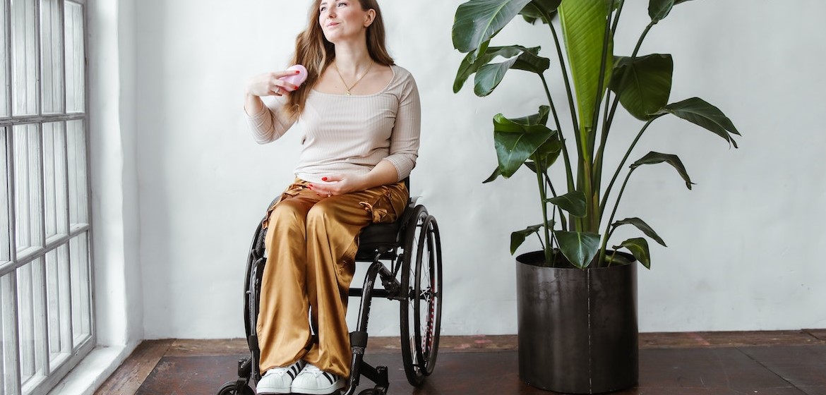 Woman Sitting on Black Wheel Chair Brushing Her Hair | Goodwill Car Donations