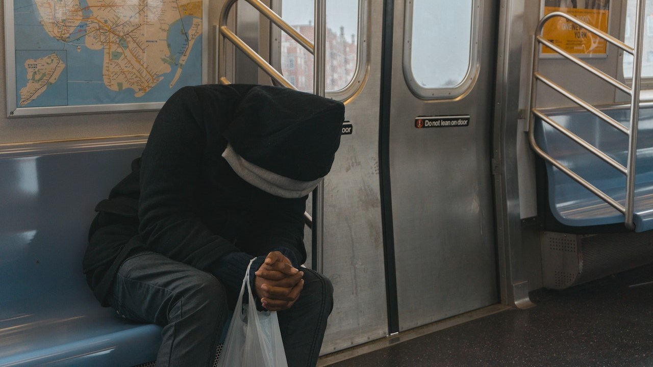 Man in a black hood sitting on the bench in the train | Goodwill Car Donations