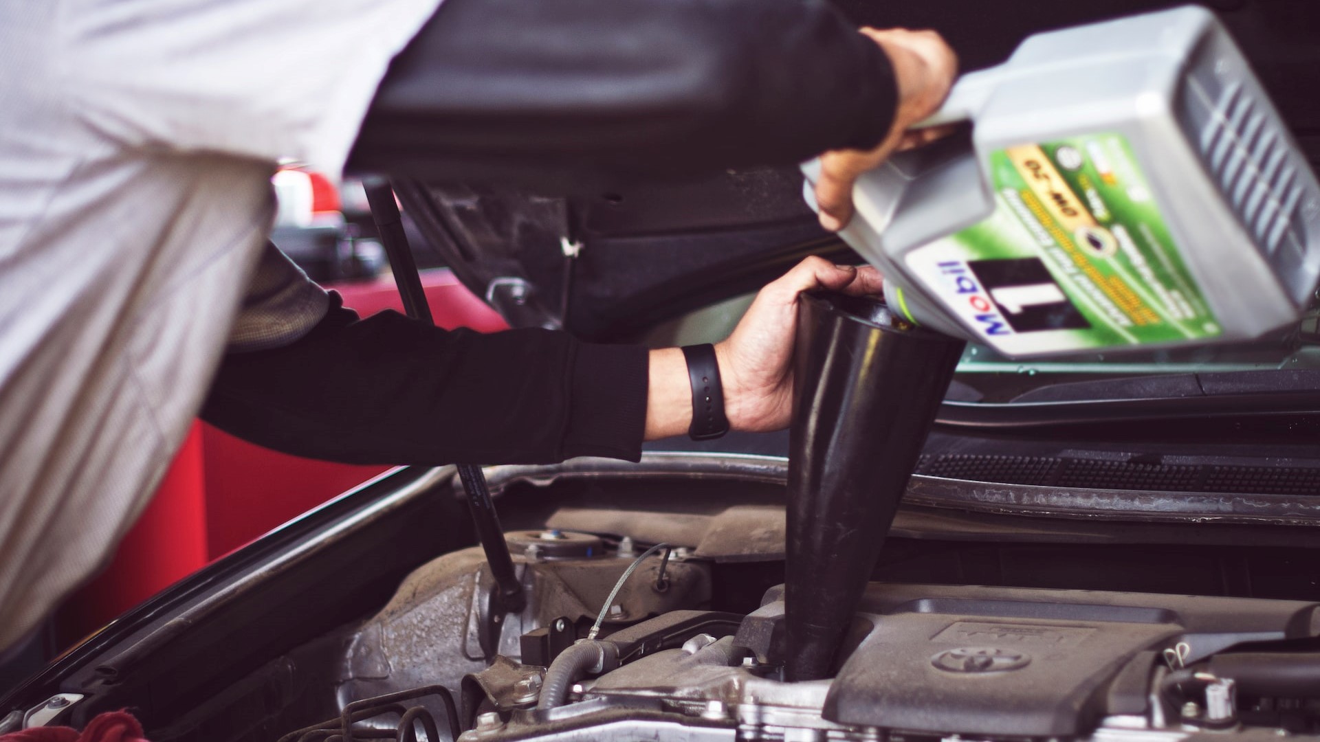 Man putting engine oil | Goodwill Car Donations