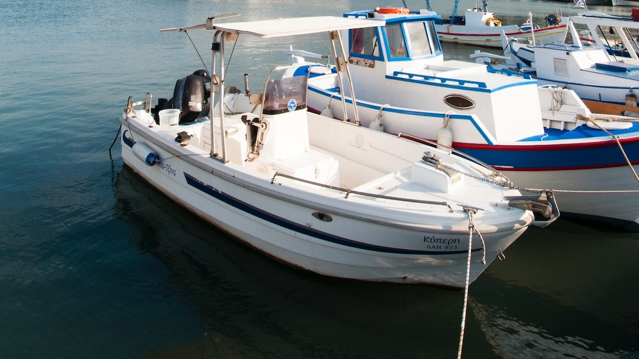 Motorized boats moored on lake under cloudy sky in port | Goodwill Car Donations