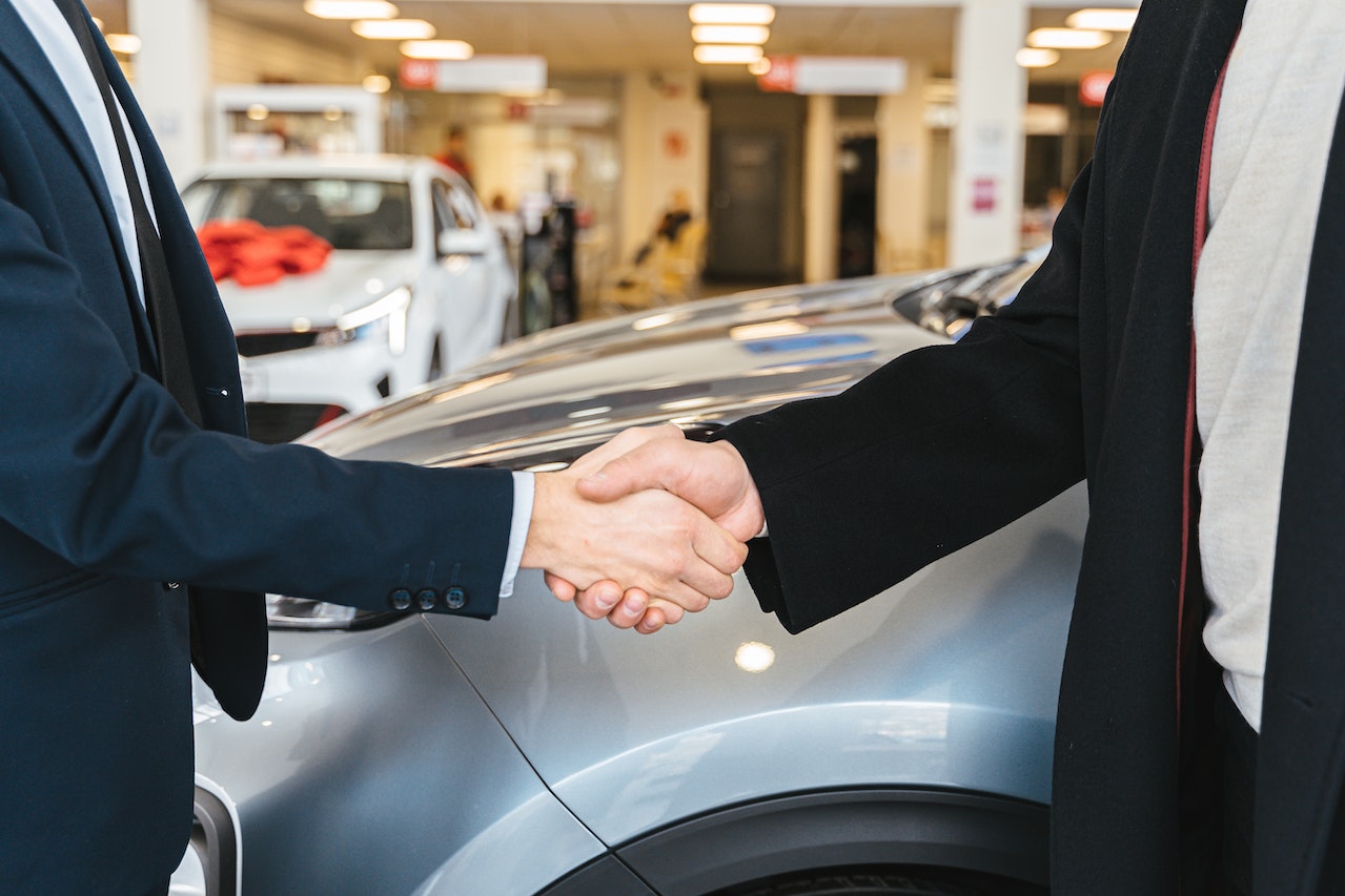 Close up of Men Shaking Hands and Cars in Background | Goodwill Car Donations