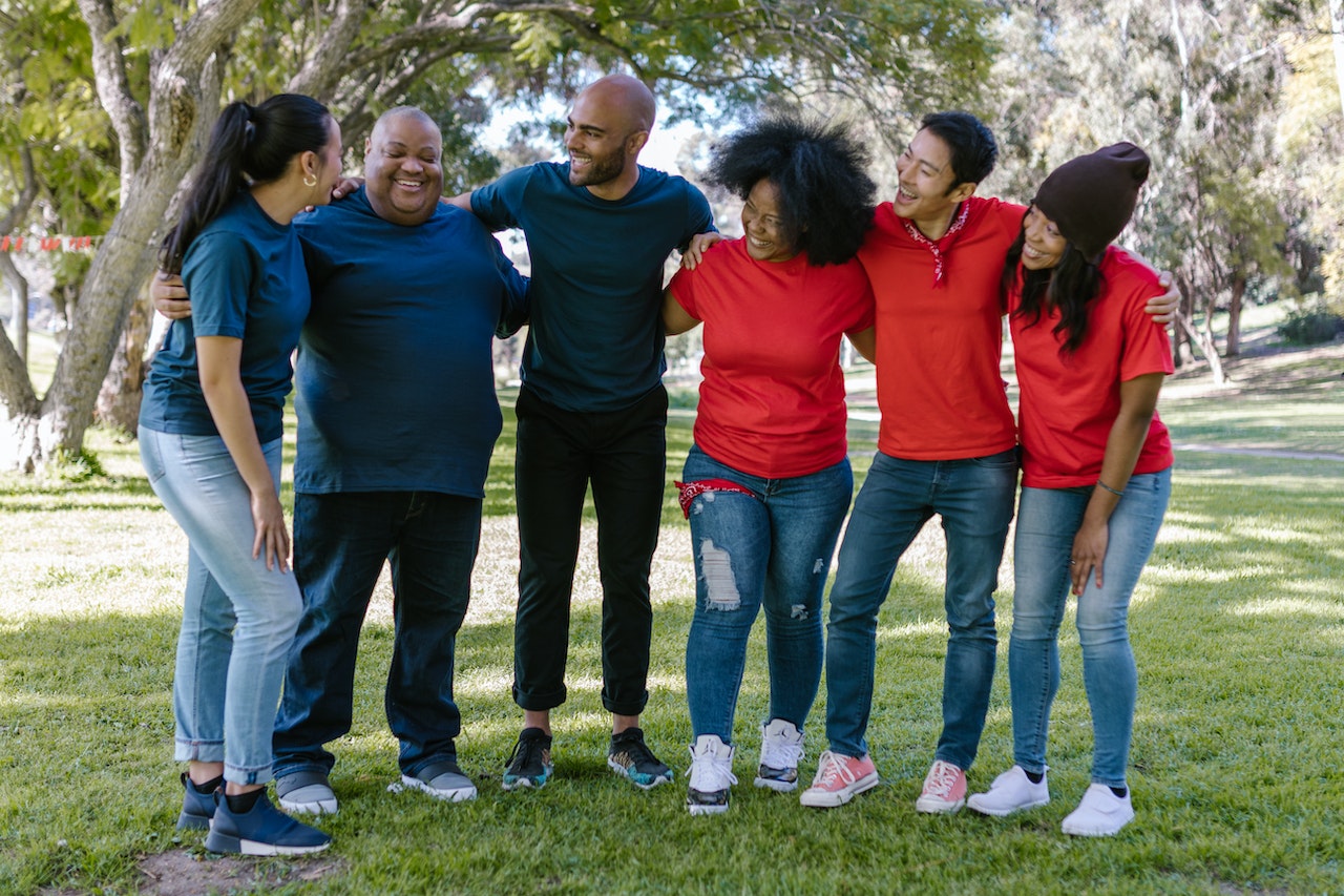 Group of People Standing on Green Grass With Happy Faces | Goodwill Car Donations