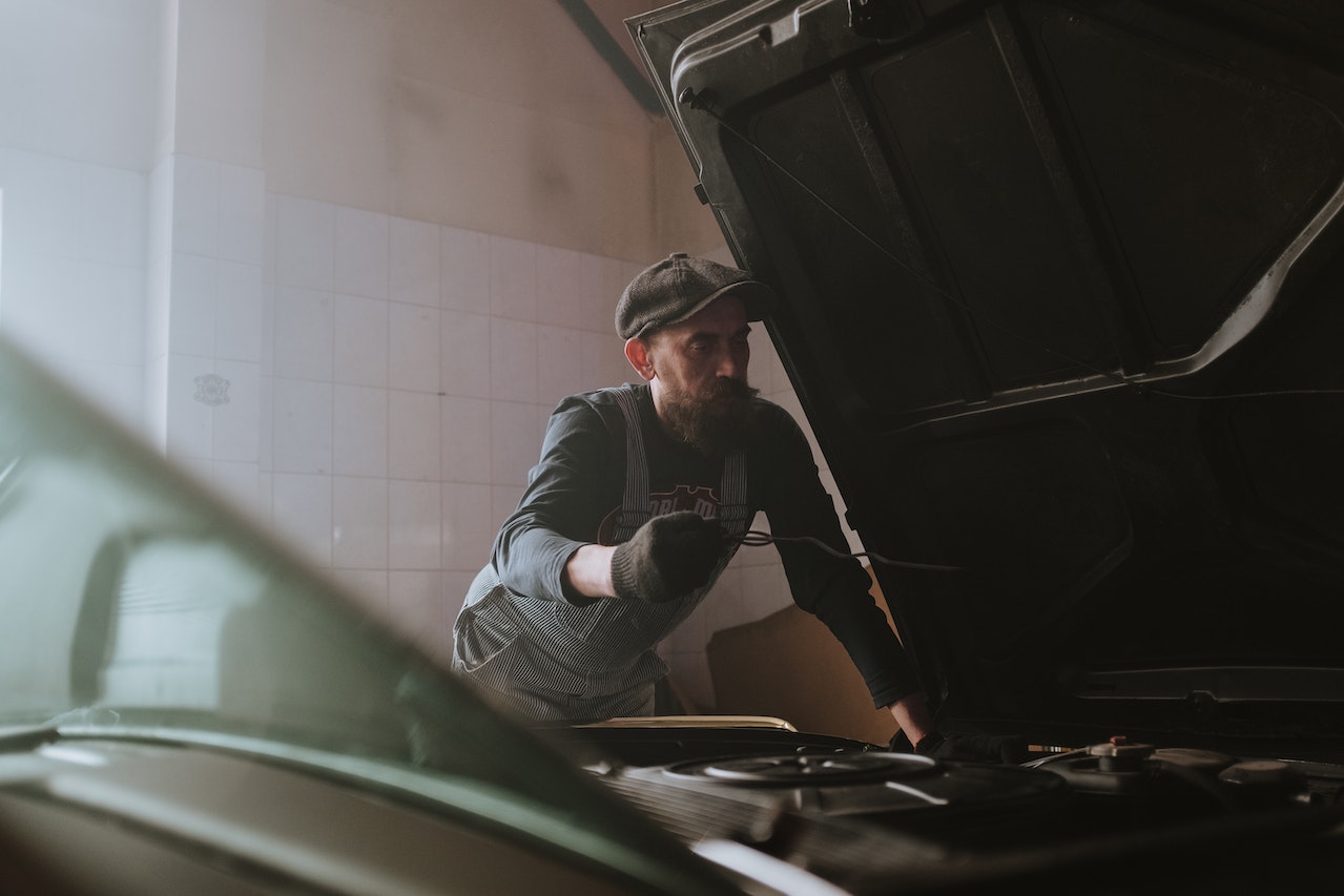 Man in Black Jacket and Black Pants Sitting on Green Car | Goodwill Car Donations