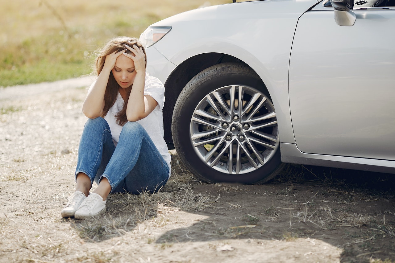 Worried young woman sitting near broken automobile at roadside in countryside | Goodwill Car Donations