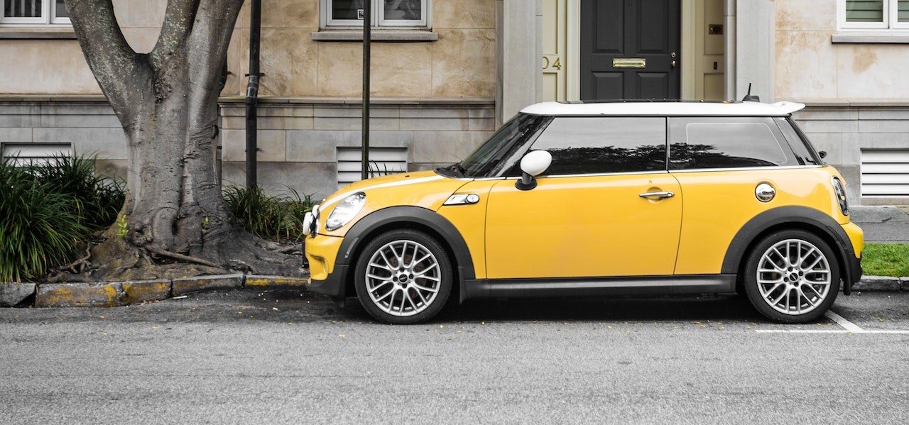 Yellow Mini Cooper Parked Beside White Concrete Building | Goodwill Car Donations