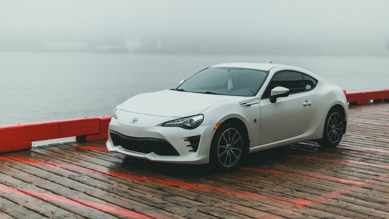 A White Coupe Car Parked on a Wooden Dock | Goodwill Car Donations