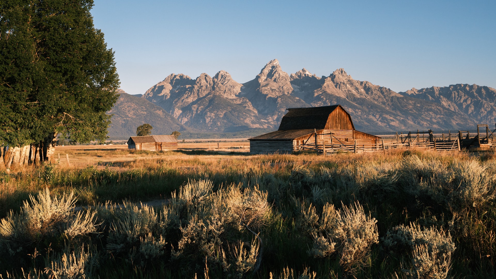 Brown wooden house on green grass field near mountain | Goodwill Car Donations