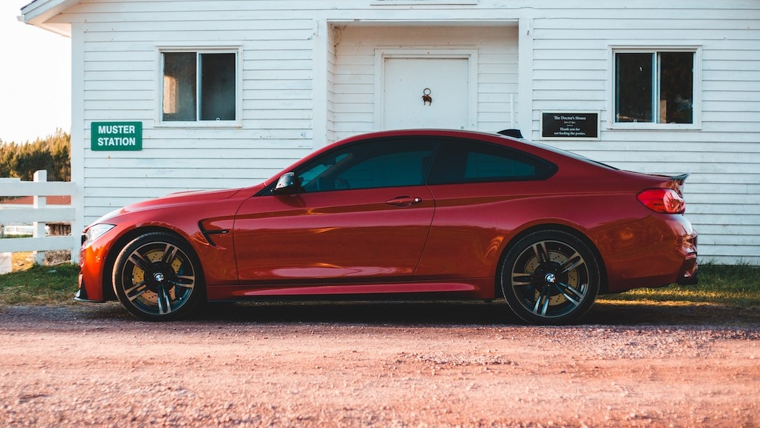 Luxury red car parked near white house in village | Goodwill Car Donations