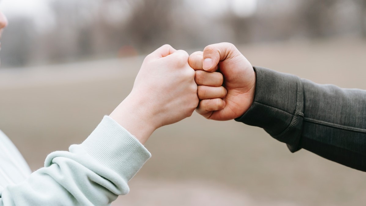 Man and happy woman greeting each other with fist bump | Goodwill Car Donations