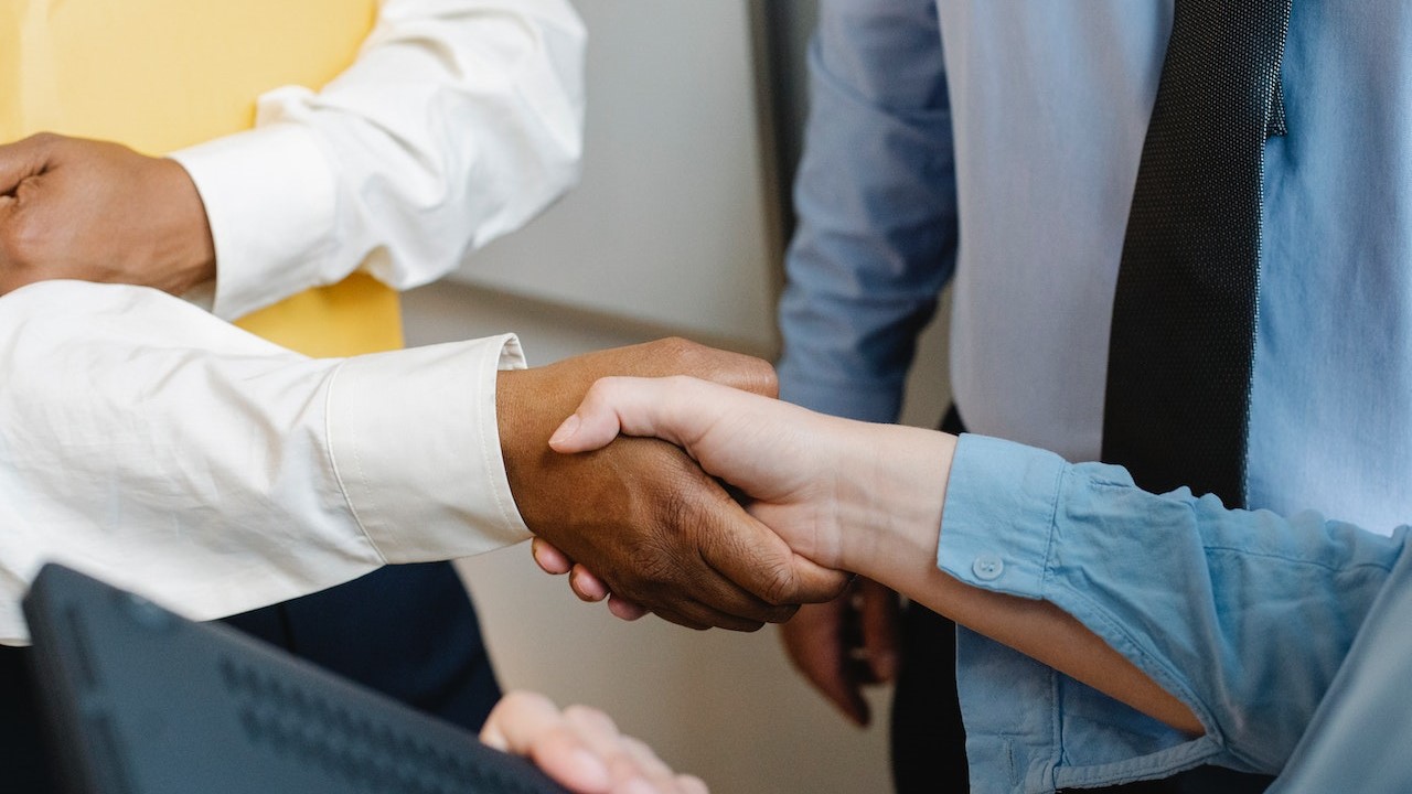 Multiracial colleagues shaking hands at work | Goodwill Car Donations