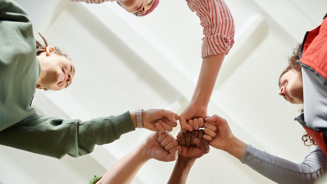 People in Circle Formation Doing Fist Bump | Goodwill Car Donations