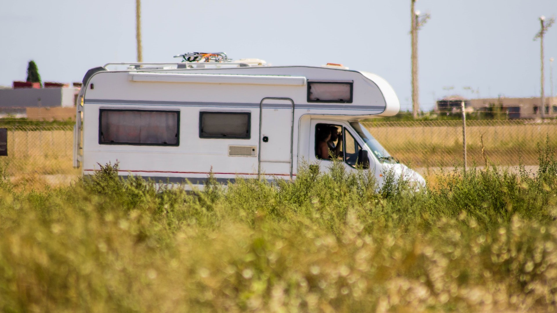 People riding a white rv on the road | Goodwill Car Donations