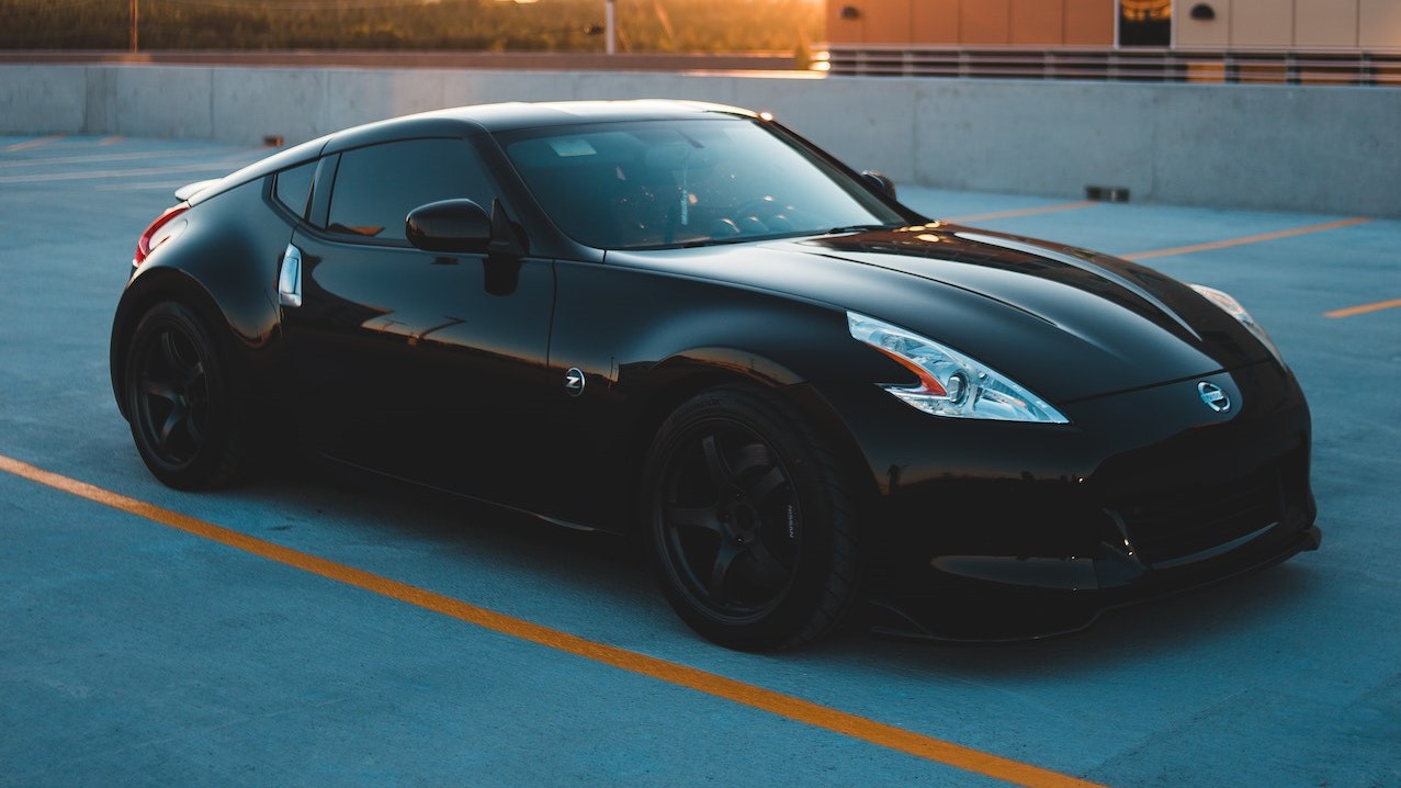 Prestigious black car parked outside industrial building at sunset | Goodwill Car Donations