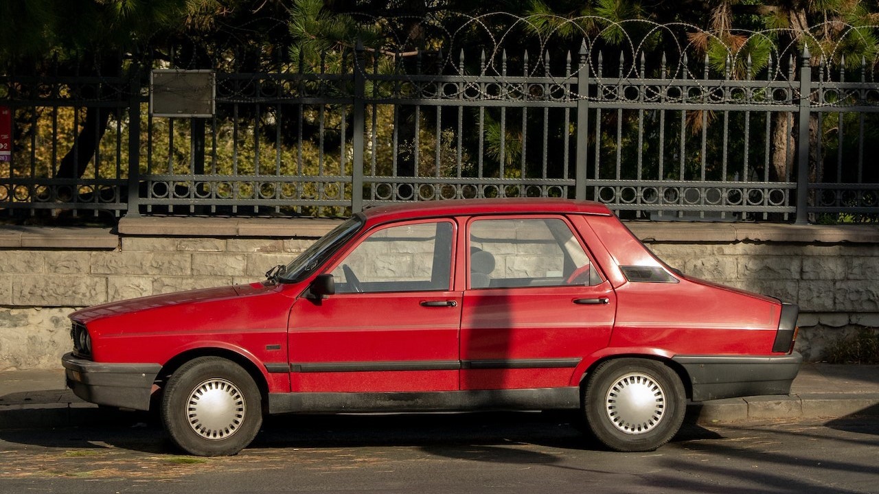 Red Sedan parked near Tree | Goodwill Car Donations