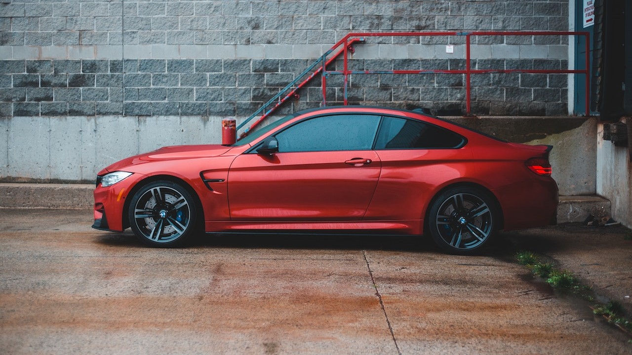 Red coupe car parked near shabby building | Goodwill Car Donations