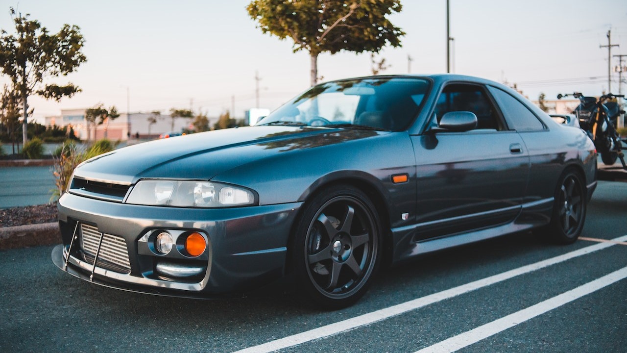 Shiny sport car driving on asphalt near green trees | Goodwill Car Donations