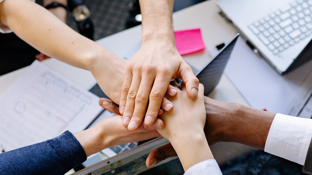 A Group of People Stacking Hands | Goodwill Car Donations