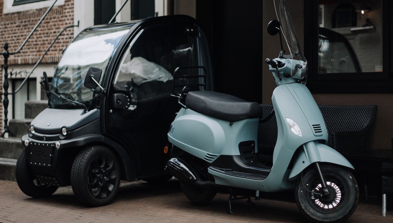 Electric Mini Car and Blue Scooter Parked Outside a House | Goodwill Car Donations