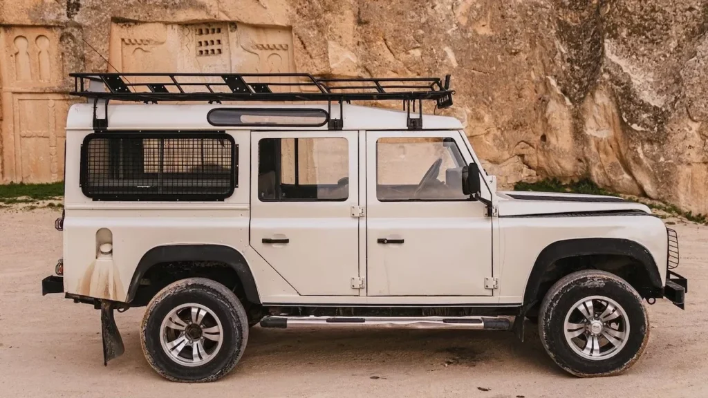 White SUV parked beside rugged rock formations in a natural landscape