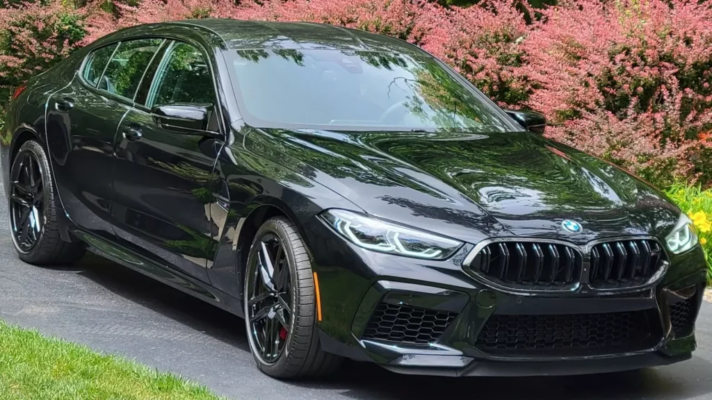 A black BMW M8 Gran Coupe is parked on the side of the road
