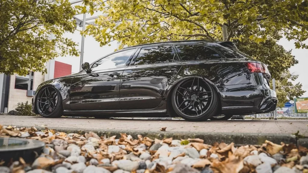 Black sedan on road with autumn leaves, showcasing modern automotive design