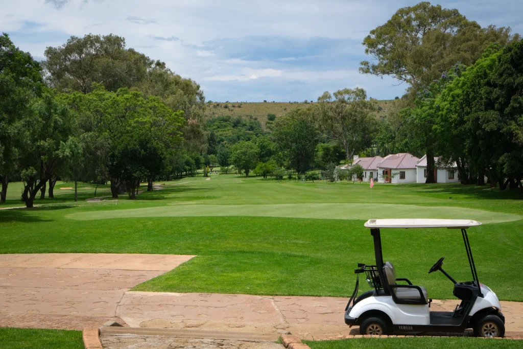 A tranquil scene of a golf course with a cart under a clear blue sky