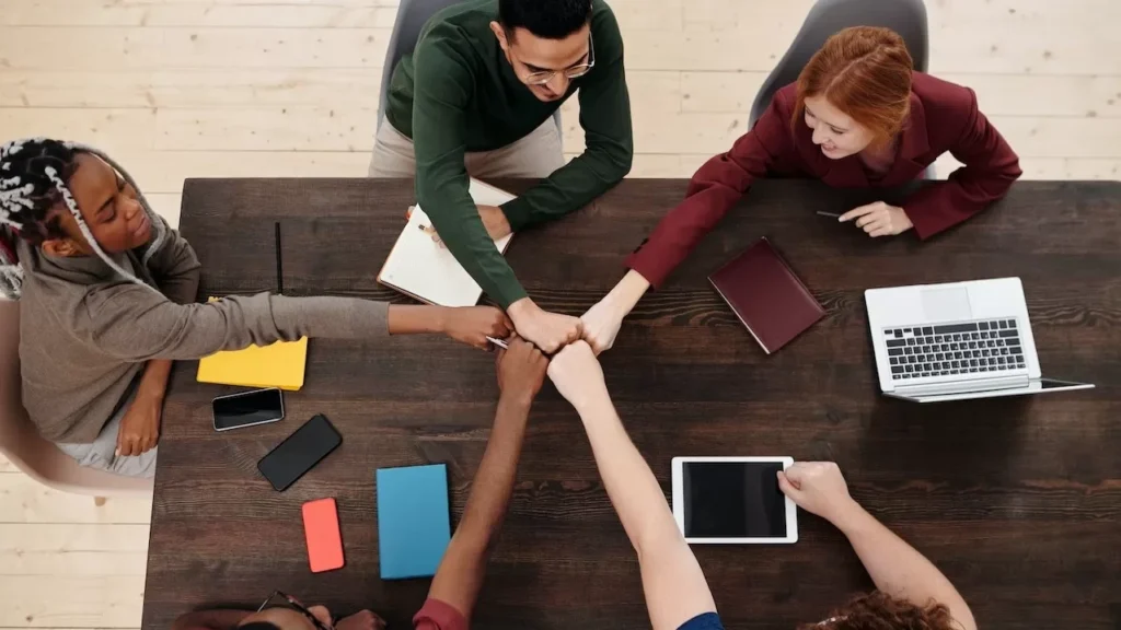 A diverse group of people in a business meeting, showing teamwork with technology on a wooden table
