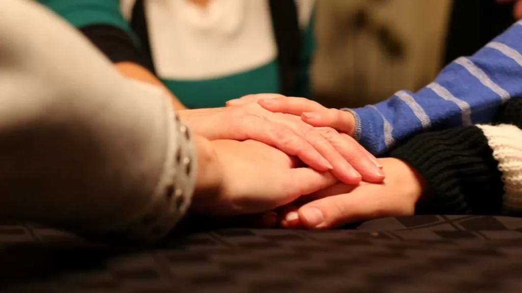 A group of people holding hands on top of a bed