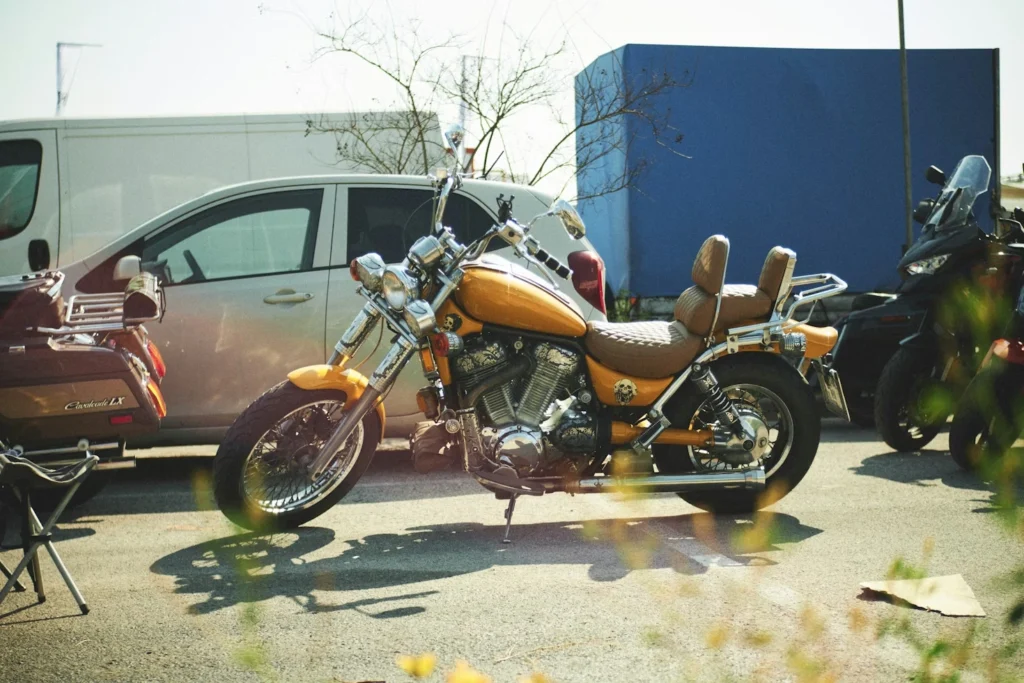 A motorcycle parked next to a car in a parking lot