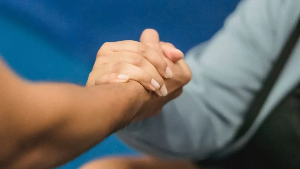 A close-up of a supportive handshake between two women in a gym setting, promoting wellness