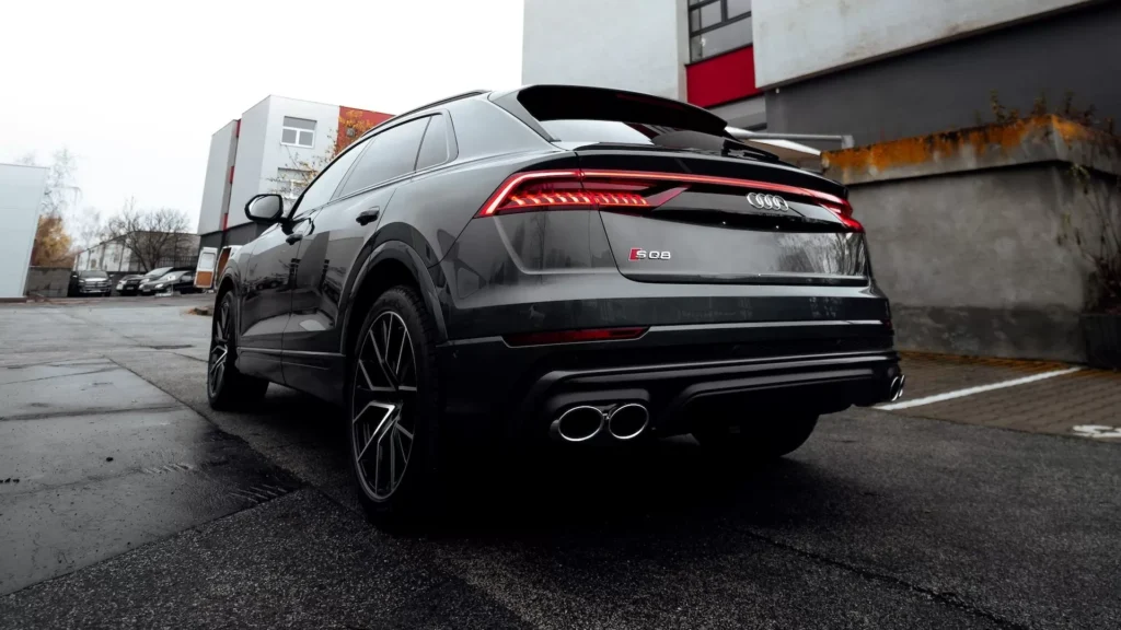 Black car parked beside white wall