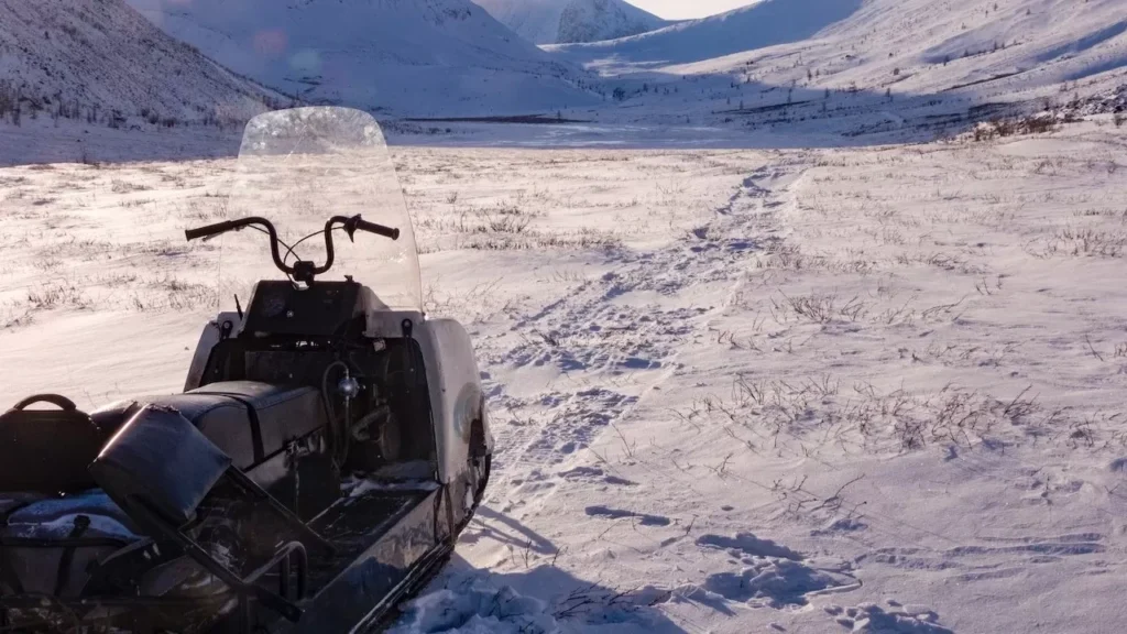Snowmobile parked on a snowy terrain with mountainous winter backdrop