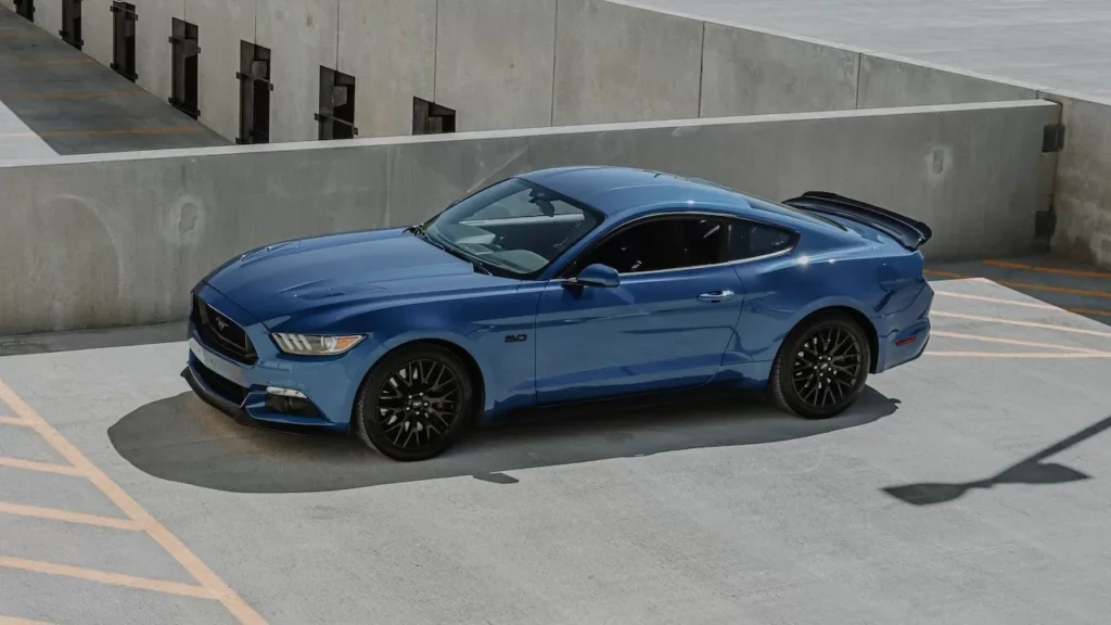 High angle view of a shiny blue Ford Mustang parked on a rooftop parking lot.