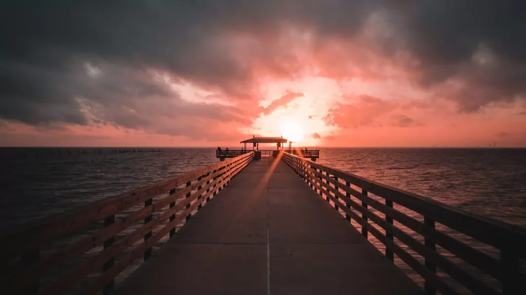 Brown wooden dock on sea during sunset
