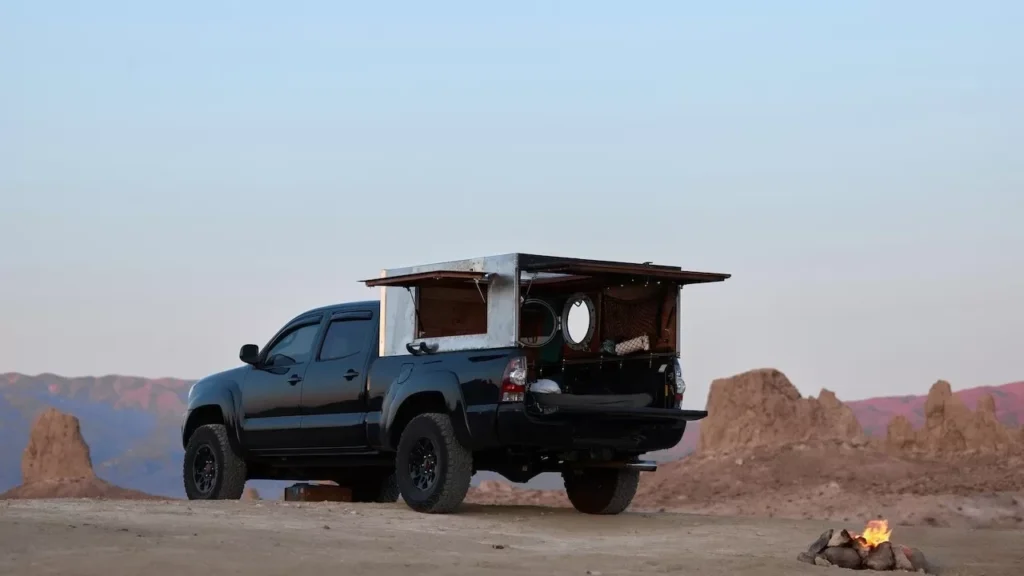 Adventure scene of an off-road pickup truck camping in a desert landscape with a small bonfire
