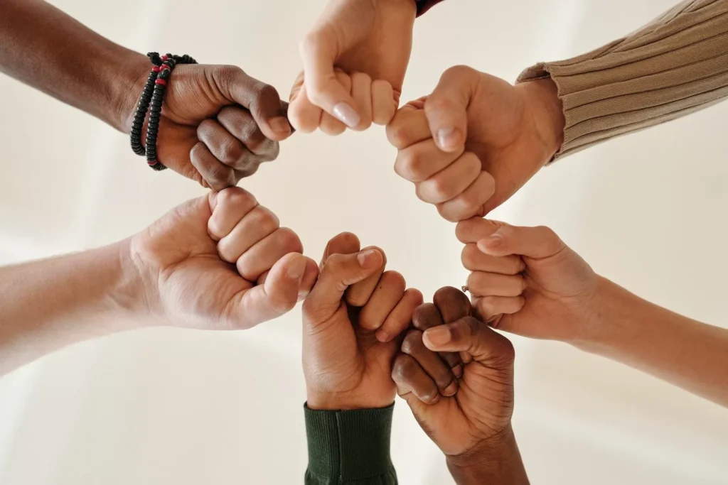 Hands of diverse people fist bumping, symbolizing unity and teamwork