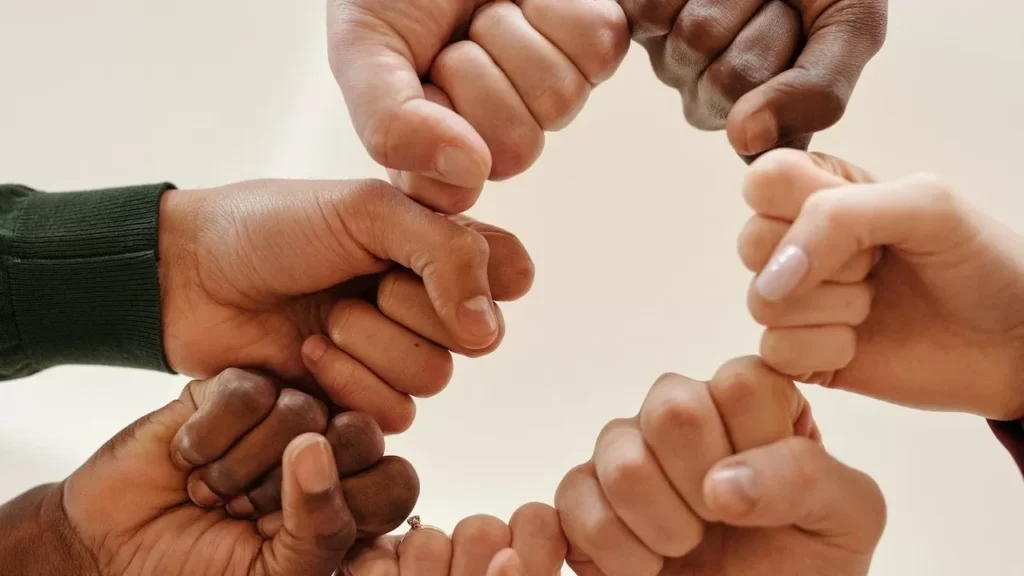Hands of diverse people fist bumping, symbolizing unity and teamwork.