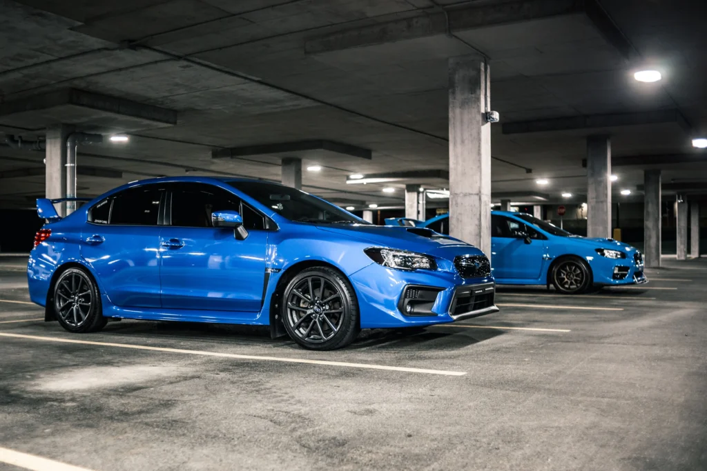 Two blue sports cars parked in a modern underground parking garage