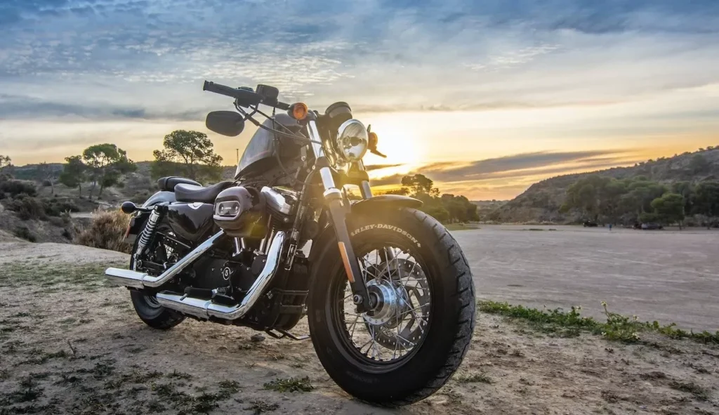 A Harley Davidson motorcycle parked outdoors against a stunning sunset sky