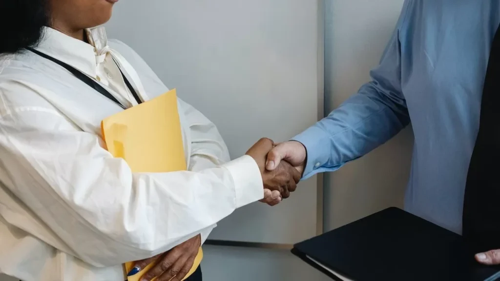 Two professionals shaking hands in an office setting, symbolizing agreement
