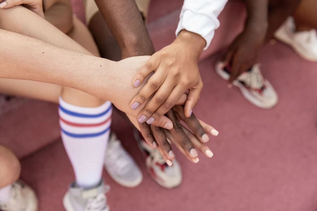 A group of friends stack their hands in unity on a sports court