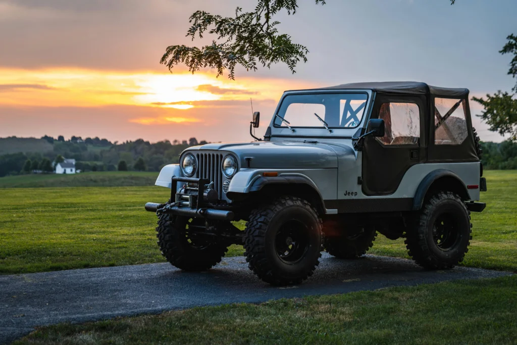 A classic Jeep parked on a rural road at sunset
