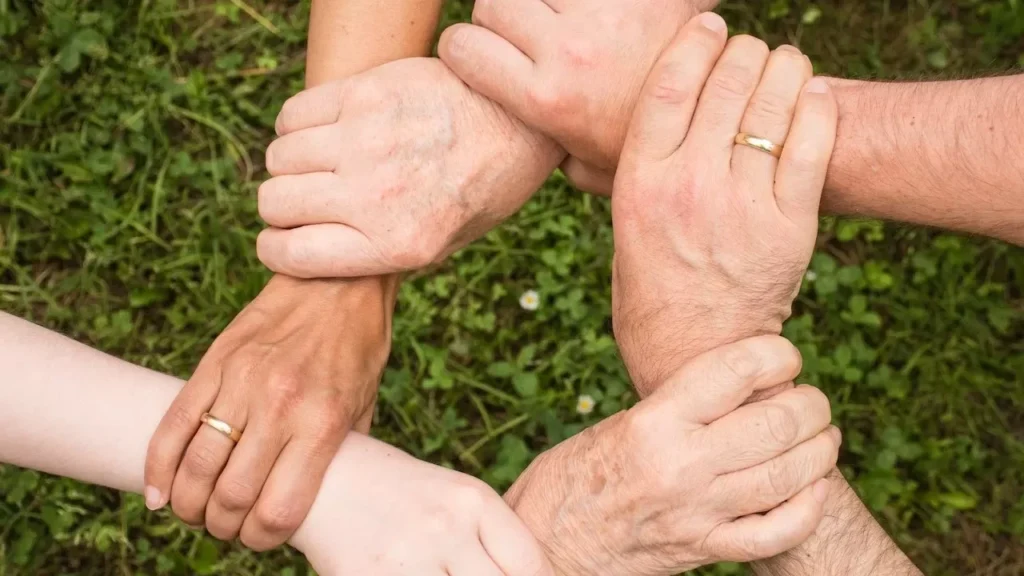 Close-up of diverse hands forming a connection, symbolizing teamwork and unity outdoors
