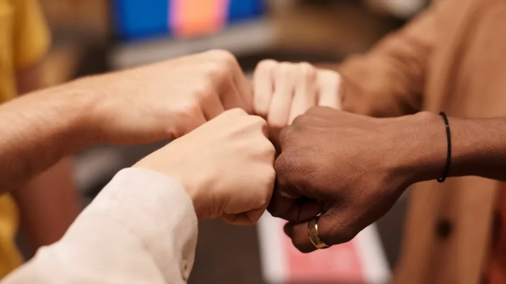 a diverse group doing a fist bump, symbolizing teamwork and unity.